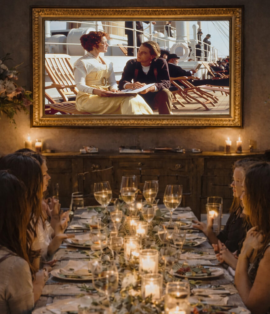 Group of ladies dining at a French community table at the Grange Garden historic cottage while watching a curated movie on a samsung frame tv for the Farm-to-Coast dinner series